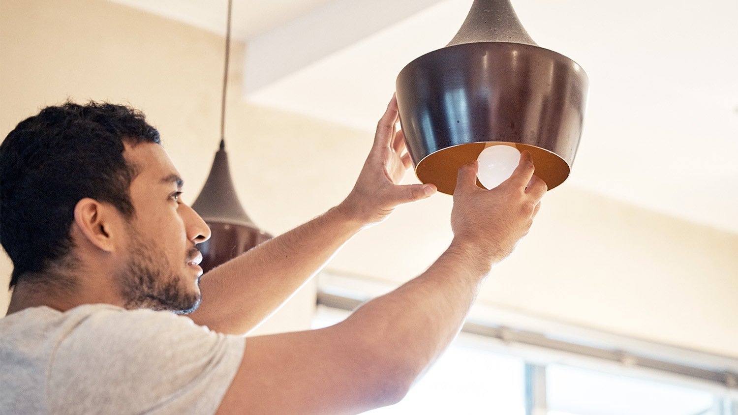 man changing lightbulb in light fixture